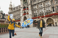 Germany, Bavaria, Munich, Couple running over place carrying balloons and bavarian flag, laughing, p - PhotoDune Item for Sale