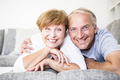 Portrait of smiling senior couple at home lying on couch - PhotoDune Item for Sale
