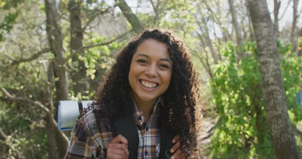 Portrait of smiling biracial woman in forest during hiking in countryside