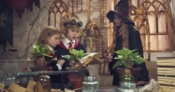 Two Little Children are Reading a Book in Class of a Magic School Teacher