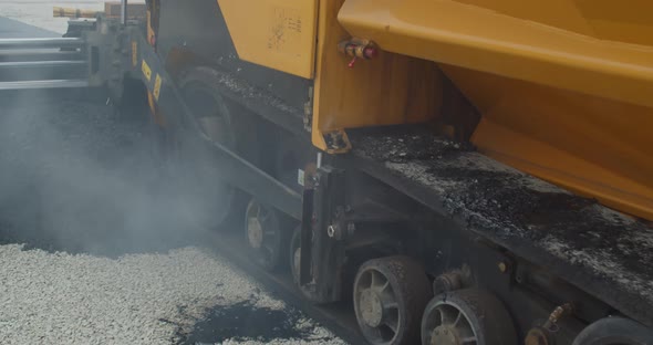Close Up of a Heavy Machine Leveling Hot Asphalt Road Work Construction