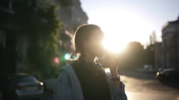 A Girl in Stylish Glasses Eats Ice Cream in a Waffle Cone in the Rays of Sunset