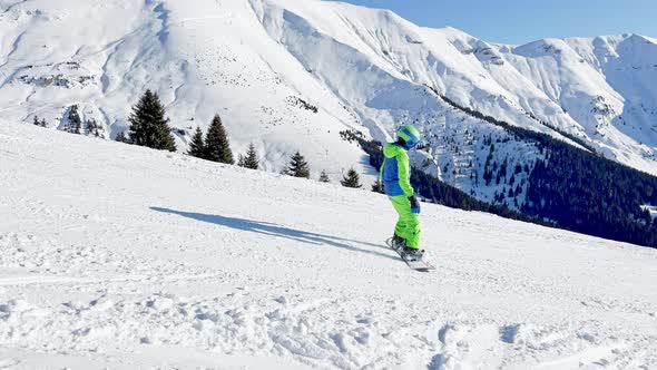 Side View Over Mountain Tops of Boy Ride on Snowboard