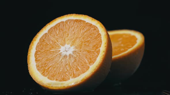 Half of a Juicy Orange Rotates in a Circle on a Black Background