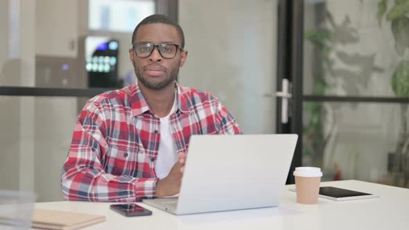 African Man Smiling at Camera While Using Laptop