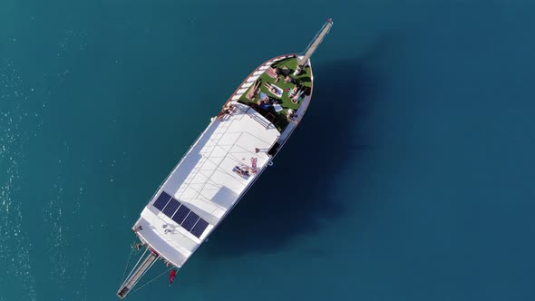 Top View of a Large Yacht in the Blue Waters of the Sea and Tourists Having a Rest on the Deck