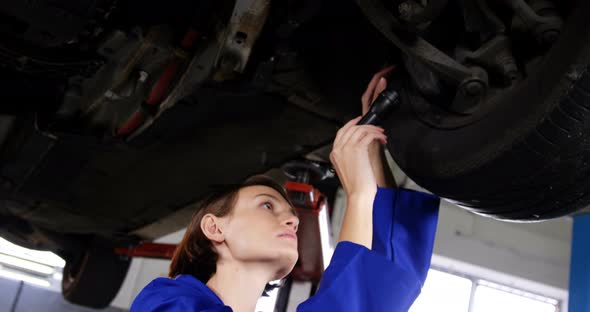 Female mechanic examining car wheel brake disc