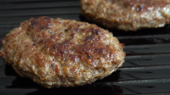 The fried cutlet for hamburger rotates on the grill pan.