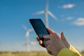 ameters in focus in human hands on a blurred background of wind turbines