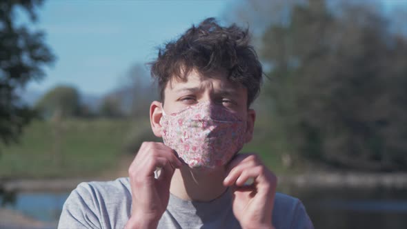 Young man puts on homemade flower pattern corona virus cotton mask MID SHOT