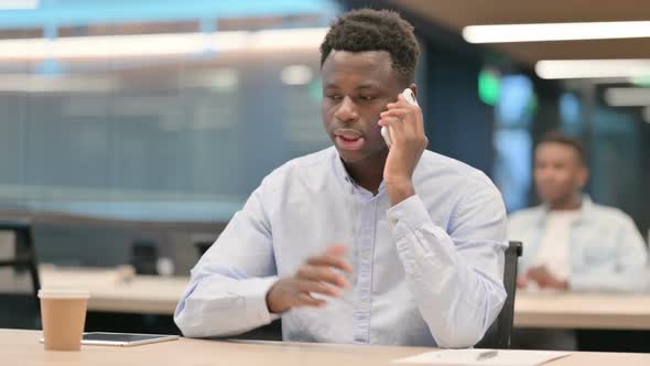 Angry African Businessman Talking on Smartphone in Office