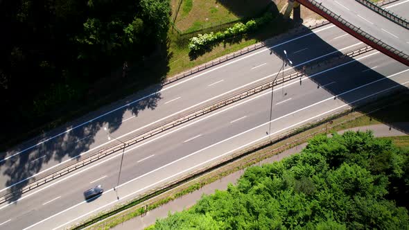 Aerial view of cars running on expressway with overhead bridge on bright sunny day.