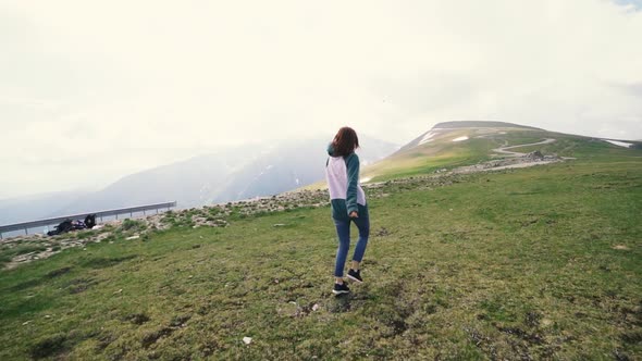 A Young Woman Hiker Running and Spinning on Top of a Mountain