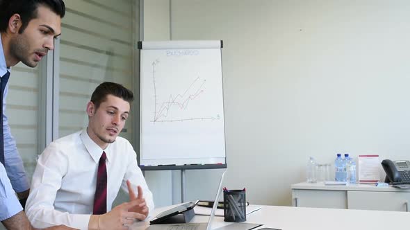 slow motion two young business man indoor office interior using personal computer discussing