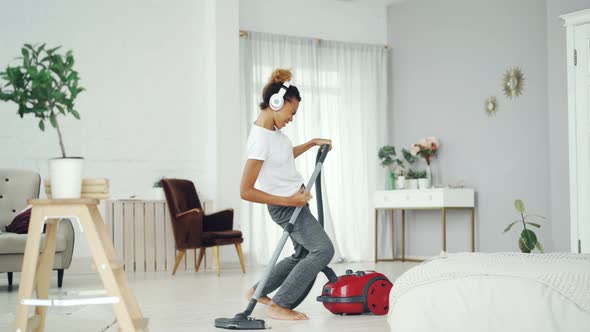 Joyful Mixed Race Girl Is Hoovering Floor in Modern House and Enjoying Rock Music Singing and