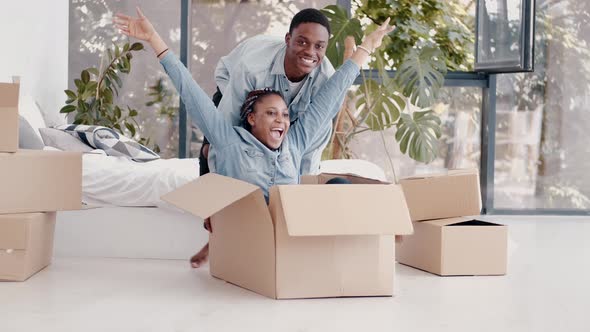 African-American Couple Are Playing with Boxes in Apartment