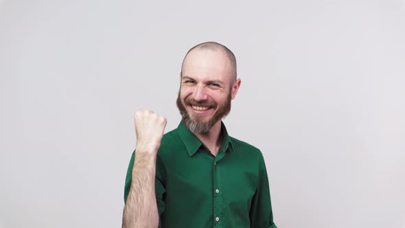 Successful man celebrating a victory and raising clenched fist in the air over white background.