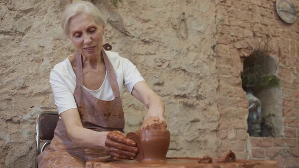 Senior Woman Potter Sculpts a Clay Pot