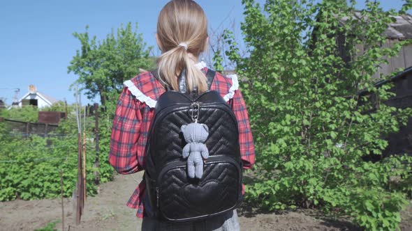 A Girl a Primary School Student with a School Bag on Her Shoulders