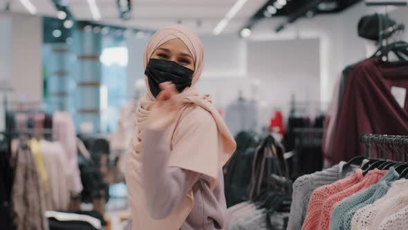 Carefree Young Arab Woman Buyer Wearing Medical Protective Mask Walking Shopping on Clothing Store