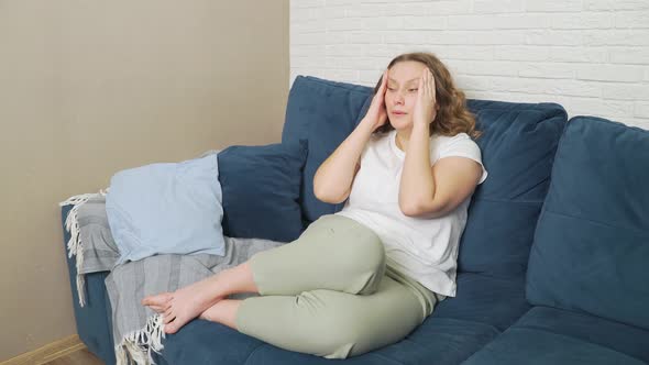 Young Woman is Sitting on the Bed She Has Migraine