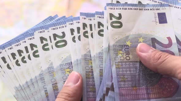 Man holding euro paper currency and counting 20 euro banknotes