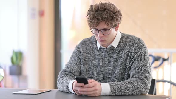 Young Man Using Smartphone at Work