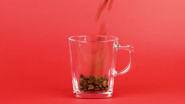 Coffee Beans Quickly Pour, Transparent Glass Mug, Red Background. Energy Concept