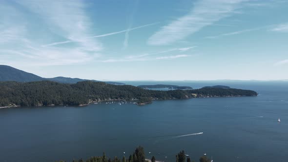 Hiker sitting atop Soames Hill looking out over the beautiful ocean in Gibsons, Canada. Aerial flyov