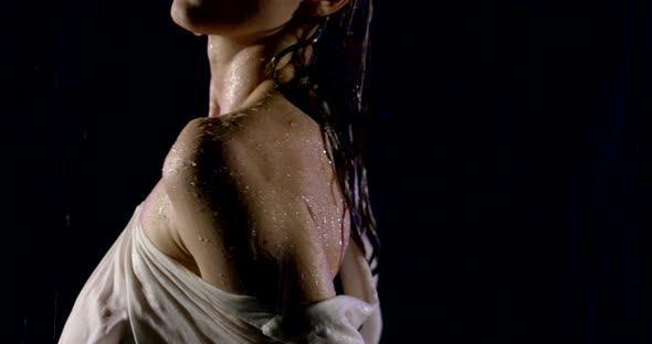 Portrait of a Wet Beautiful Girl Close-up. She Stands on a Black Background in the Pouring Rain. It