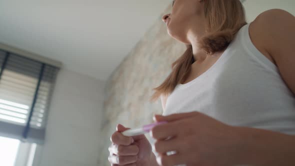 Low angle view of young woman holding pregnancy test and waiting for results. Shot with RED helium c