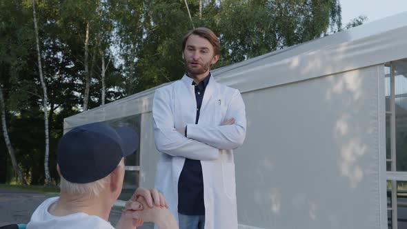 Handsome Young Doctor Speaks with His Patient