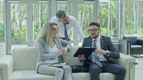 Cheerful Businesspeople Discussing Information on Clipboard