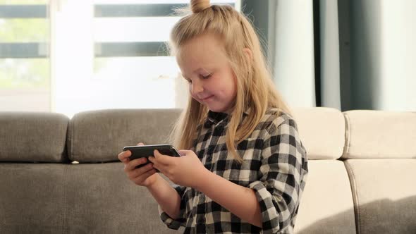 Little girl child emotionally plays mobile games using phone. Addiction to online