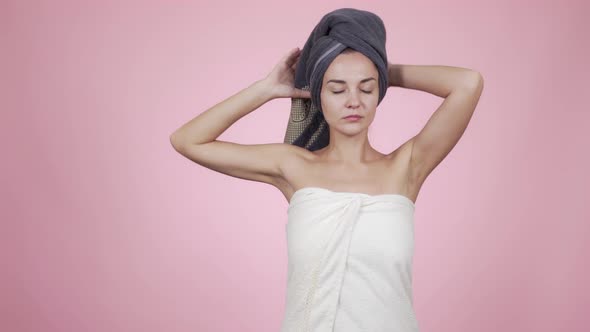 Woman with Towel on Head Stretching Hands Up and Yawning, Did Not Get Enough Sleep, Isolated on Pink