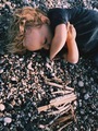 Little child collecting driftwood lying on the beach pebbles - PhotoDune Item for Sale