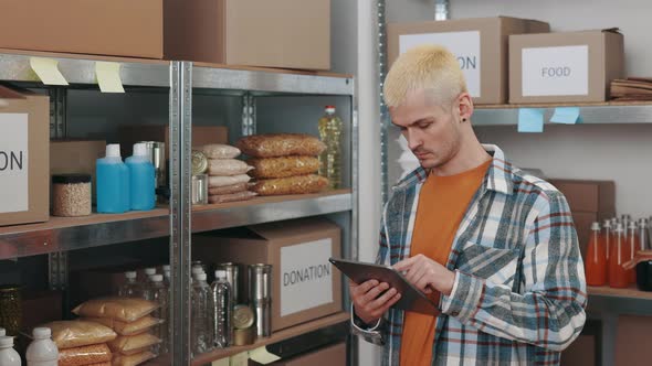 Man Using Tablet During Inspection of Food Bank Storage