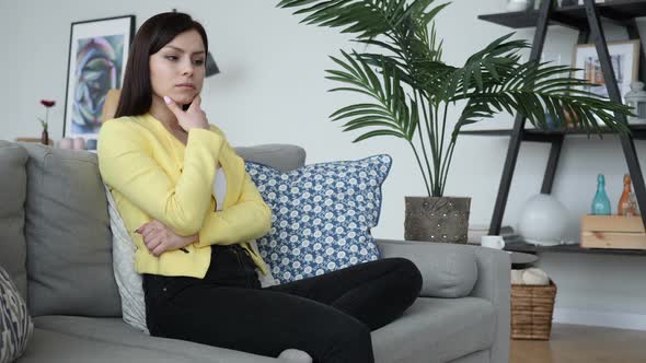 Pensive Woman Thinking While Sitting on Sofa in House