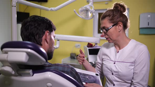 Woman Dentist Showing Patient X-ray Scan of Jaw