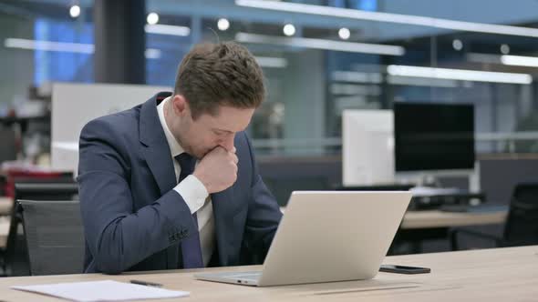 Businessman Coughing While Using Laptop in Office