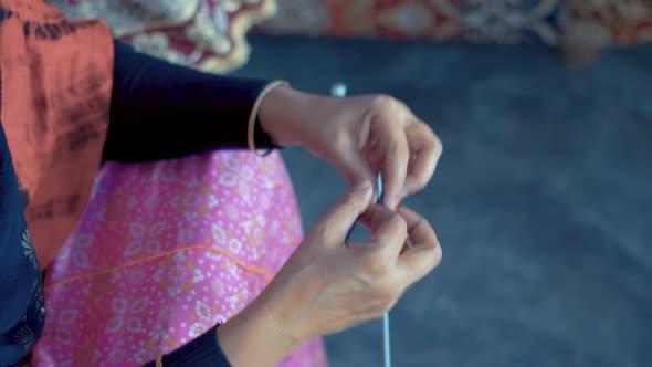 Indian woman's hands knit with red and black wool and needle crafts. Footage form above of knit work