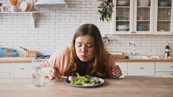 Young Plus Size Lady Eating Fresh Salad at Kitchen Drinking Water