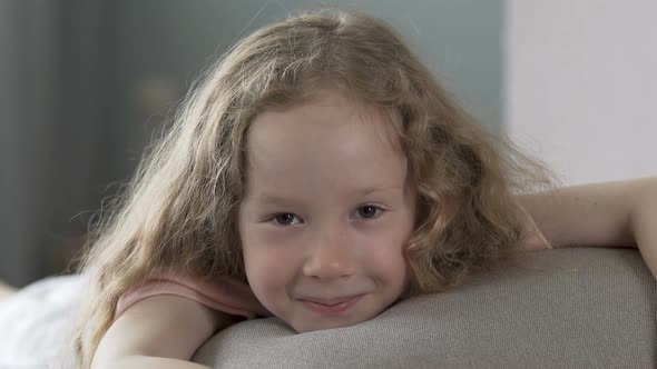 Cheerful Curly Haired Girl Lying on Sofa