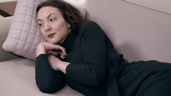 Closeup of a Woman Standing Up Lying on a Sofa on a Pillow Enjoying a Rest in a Bright Room