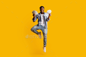 h of money cash and jumping up on yellow studio background, showing happiness, copy space. Loan, wage, salary, lottery, gaming, gambling, trading