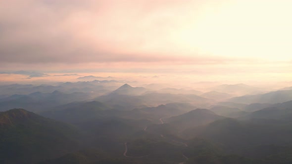 4K Flying through the clouds above mountain tops. Tropical forest with smoke and fog.