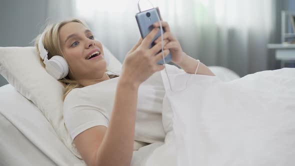 Teenager in Headphones Listening to Music in Bed, Communicating in Social Media