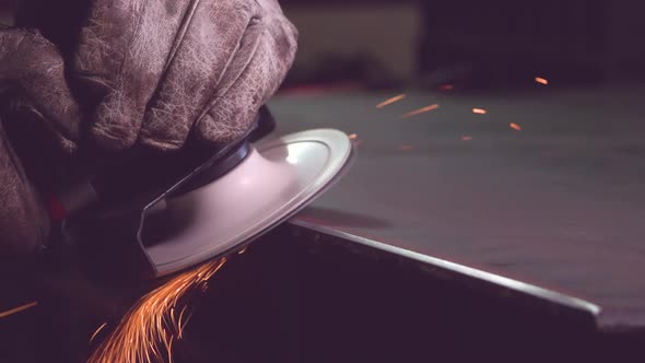 Crop metal worker in gloves grinding edge of metal handiwork