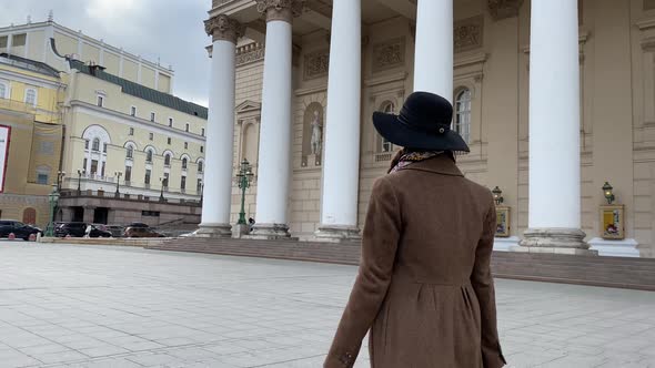 Elegant lady in hat and coat go to work, walk in Moscow center, Bolshoi Theater