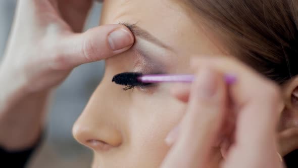 Makeup Artist Paints Natural Eyelashes with Mascara To Model in Beauty Salon